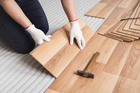 Installer installing wood floor panels